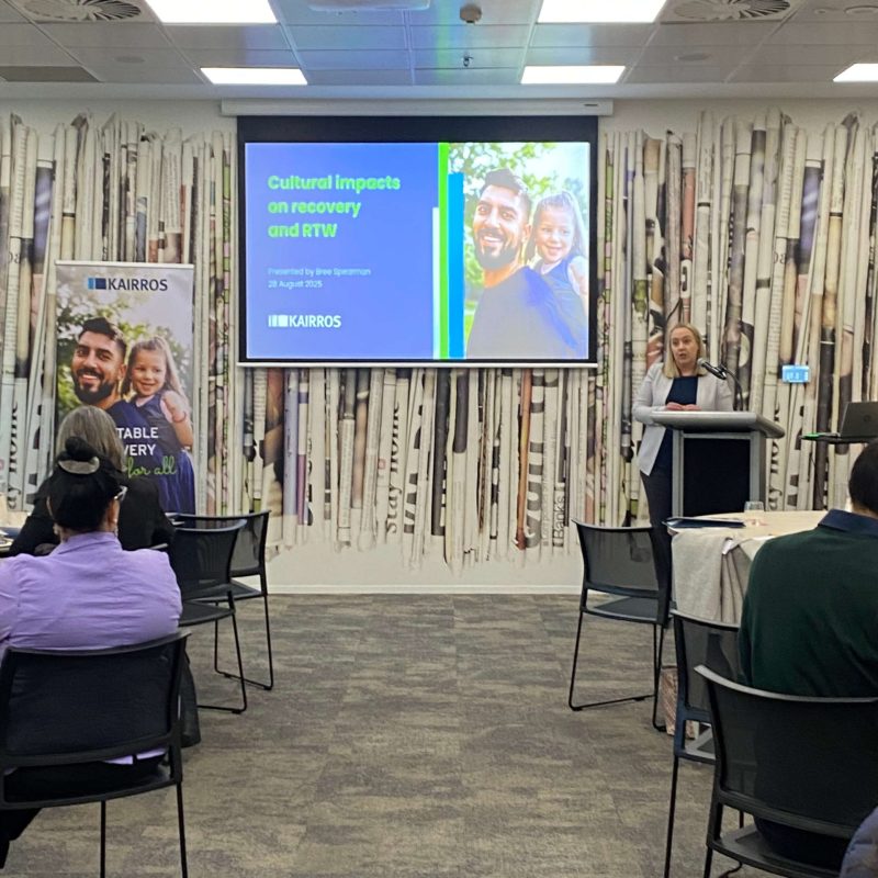 People in a training session smiling to camera with a projection in the background